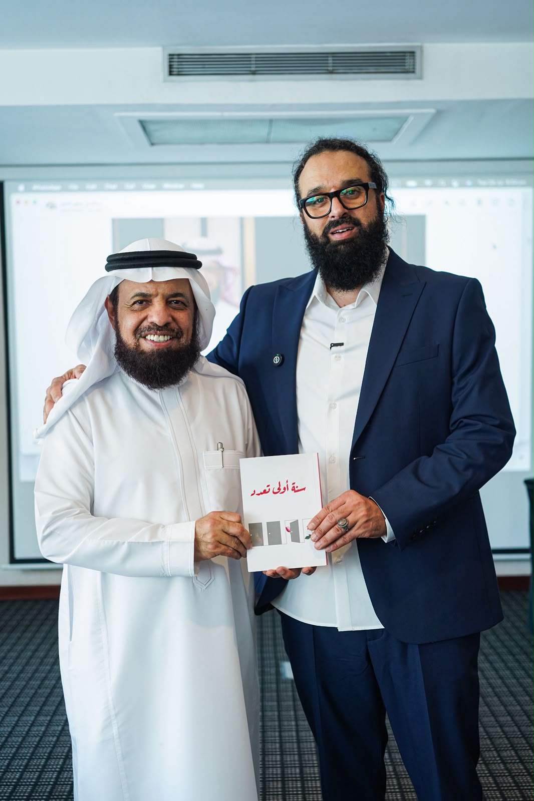 د. حامد الإدريسي مع أحد المشاركين يحملان كتابًا